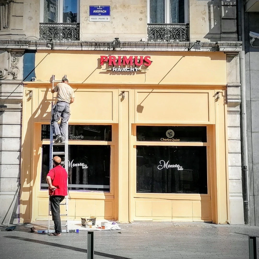 Photo : un homme repeint la façade d'un café de Bruxelles. Photo A. Maneuvrier 2020